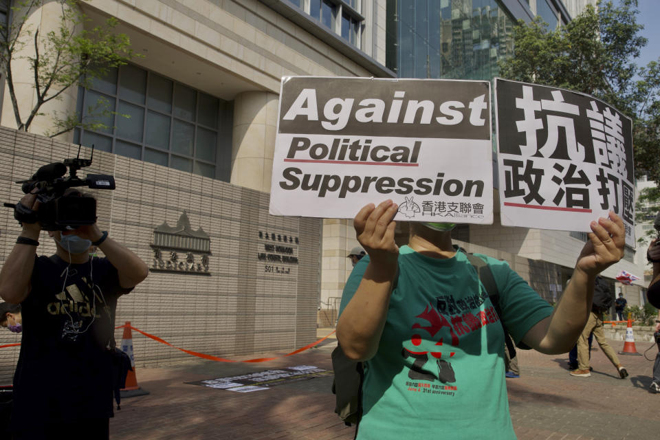 A pro-democracy supporter raises placards outside a court in Hong Kong Thursday, April 1, 2021. Seven pro-democracy advocates were convicted Thursday for organizing and participating in an unlawful assembly during massive anti-government protests in 2019, as Hong Kong continues its crackdown on dissent. (AP Photo/Vincent Yu)