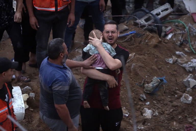 Un hombre palestino llora mientras sostiene en brazos a un bebé muerto encontrado bajo los escombros de un edificio destruido tras ataques aéreos israelíes al campo de refugiados de Nusseirat, en el centro de la Franja de Gaza, el 31 de octubre de 2023.
