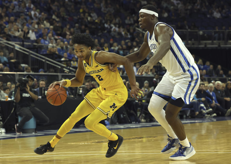 Michigan Wolverines' Kobe Bufkin (2) dribbles past Kentucky Wildcats' Oscar Tshiebwe (34) during an NCAA basketball game between Michigan Wolverines and Kentucky Wildcats at the O2 Arena, in London, Sunday, Dec.4, 2022. (AP Photo/Ian Walton)