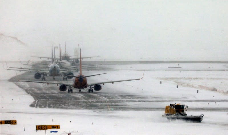 A snowplow clears a runway near a line of jets waiting to takeoff after a snowstorm at Denver International Airport