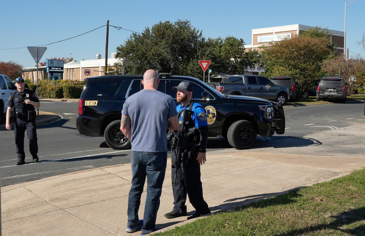 An Austin police officer talks to a concerned man after a shooting at Northeast Early College High School on Tuesday December 5, 2023.