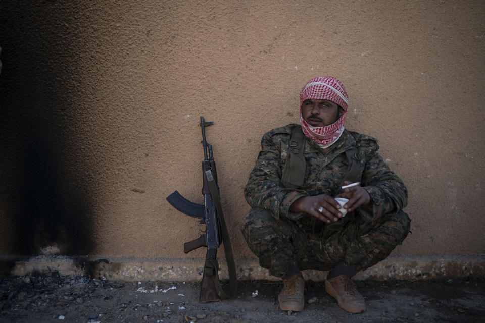 A U.S.-backed Syrian Democratic Forces (SDF) fighter sits inside a building used as a temporary base near the last land still held by Islamic State militants in Baghouz, Syria, Monday, Feb. 18, 2019. Hundreds of Islamic State militants are surrounded in a tiny area in eastern Syria are refusing to surrender and are trying to negotiate an exit, Syrian activists and a person close to the negotiations said Monday. (AP Photo/Felipe Dana)