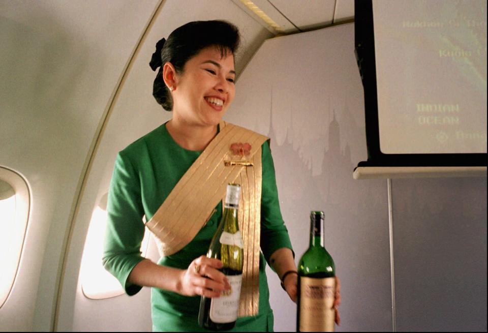 FILE - In this Dec. 14, 1996, file photo, a Thai Airways International airline flight attendant offers a passenger a selection of wine during a flight from Singapore to Bangkok. Airlines have found a way to take the edge off the stress of flying and make a few extra bucks along the way: fancy new cocktails, craft beers and elegant wines. (AP Photo/Richard Vogel)