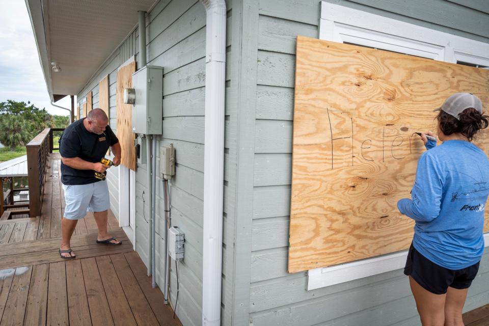 Bill and Mandy Adams board up their home before evacuating from Hurricane Helene on September 26, 2024 in Keaton Beach, Florida.