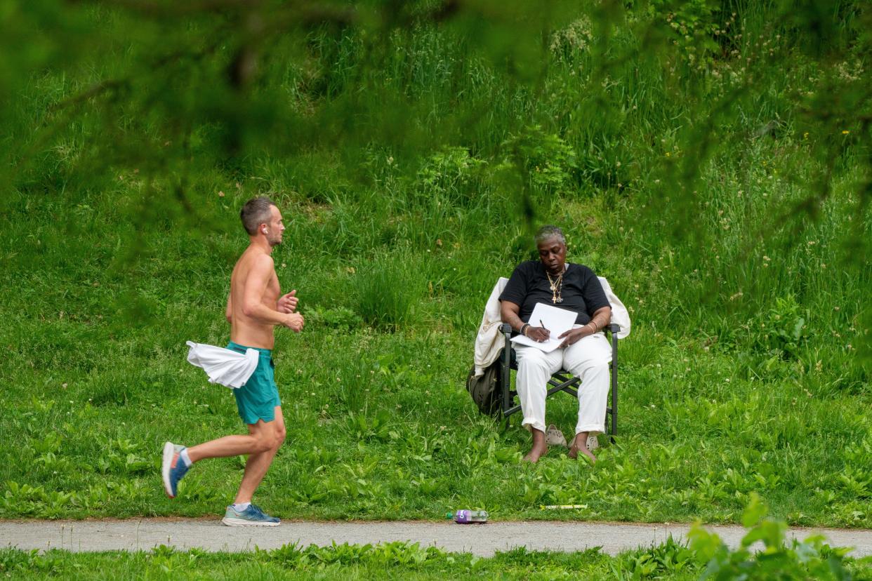 A jogger runs past a person drawing in Central Park on Sunday.