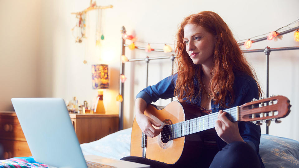   Una mujer aprendiendo guitarra en línea. 