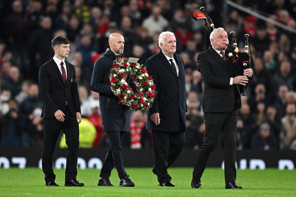 Erik ten Hag carries a wreath of flowers next to  Alex Stepney and Dan Gore during a tribute to late Bobby Charlton (AFP via Getty Images)