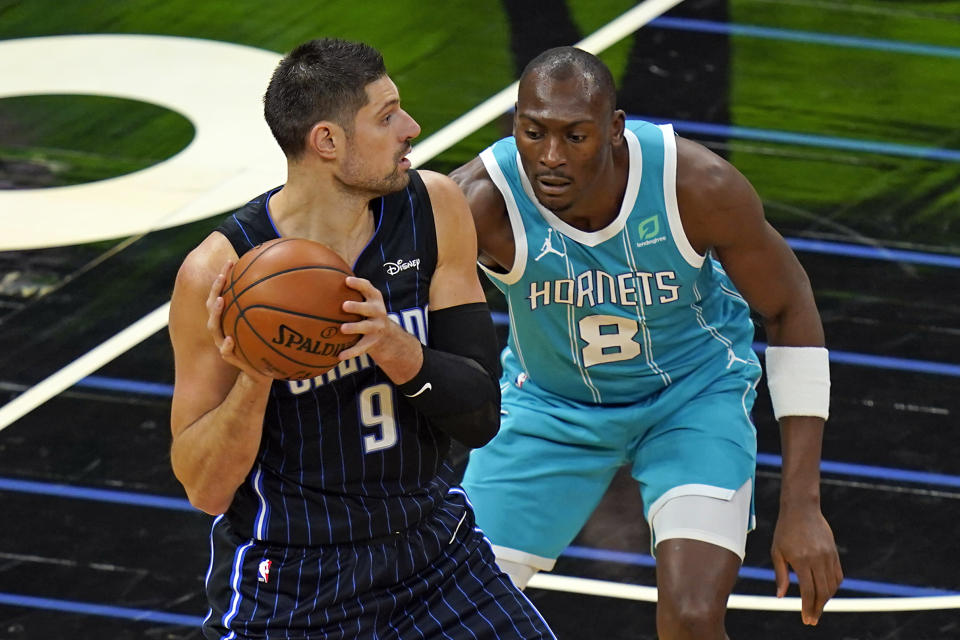 Orlando Magic center Nikola Vucevic (9) looks to pass the ball as Charlotte Hornets center Bismack Biyombo (8) defends during the first half of an NBA basketball game, Monday, Jan. 25, 2021, in Orlando, Fla. (AP Photo/John Raoux)