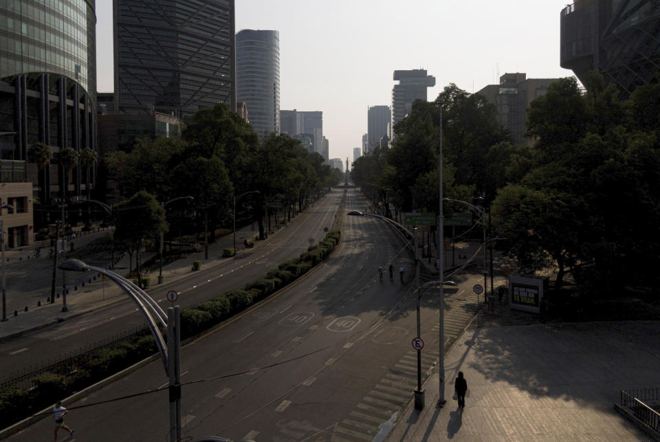 People jog at an empty Paseo de la Reforma in Mexico City, Sunday, April 26, 2020. (AP Photo/Fernando Llano)