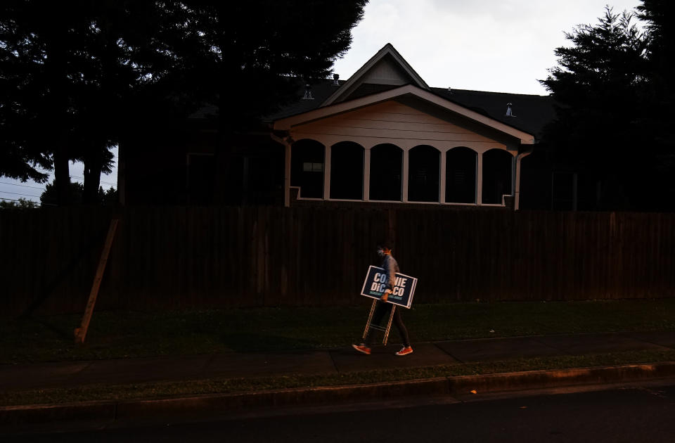 Georgia State Representative and Democratic candidate of District 44, Connie Di Cicco walks with a campaign sign through a neighborhood on Sunday, Oct. 11, 2020, in Marietta, Ga. Calling themselves sign ninjas, a group of people, including Di Cicco, routinely gather to trade and assemble campaign signs around their districts for local elections in Georgia and then venture out in the dark to install them along main thoroughfares. (AP Photo/Brynn Anderson)