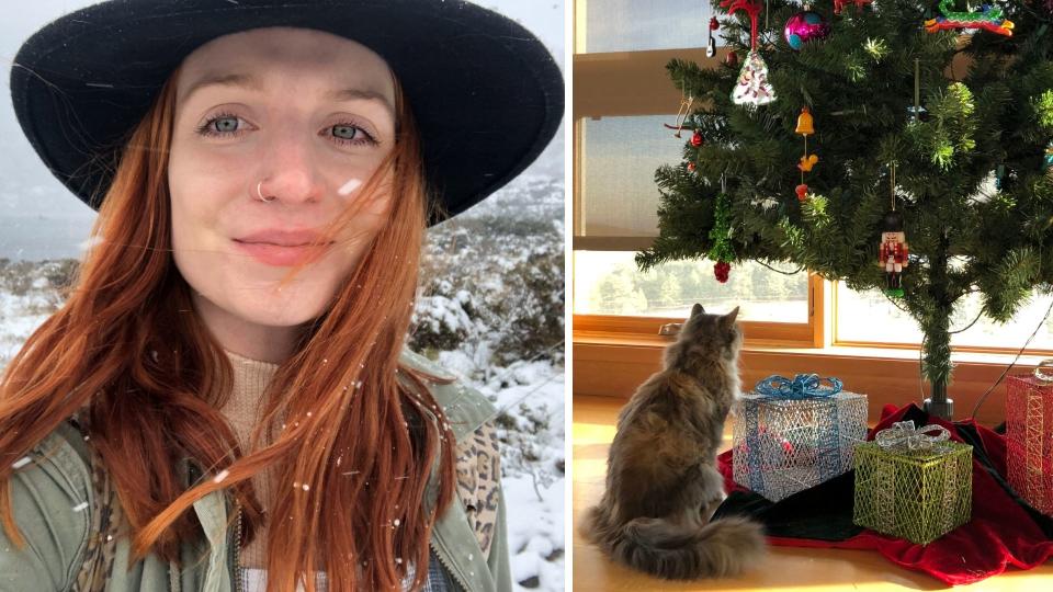 Madolline Gourley in the snow with black hat on. Cat sitting beneath Christmas tree. 