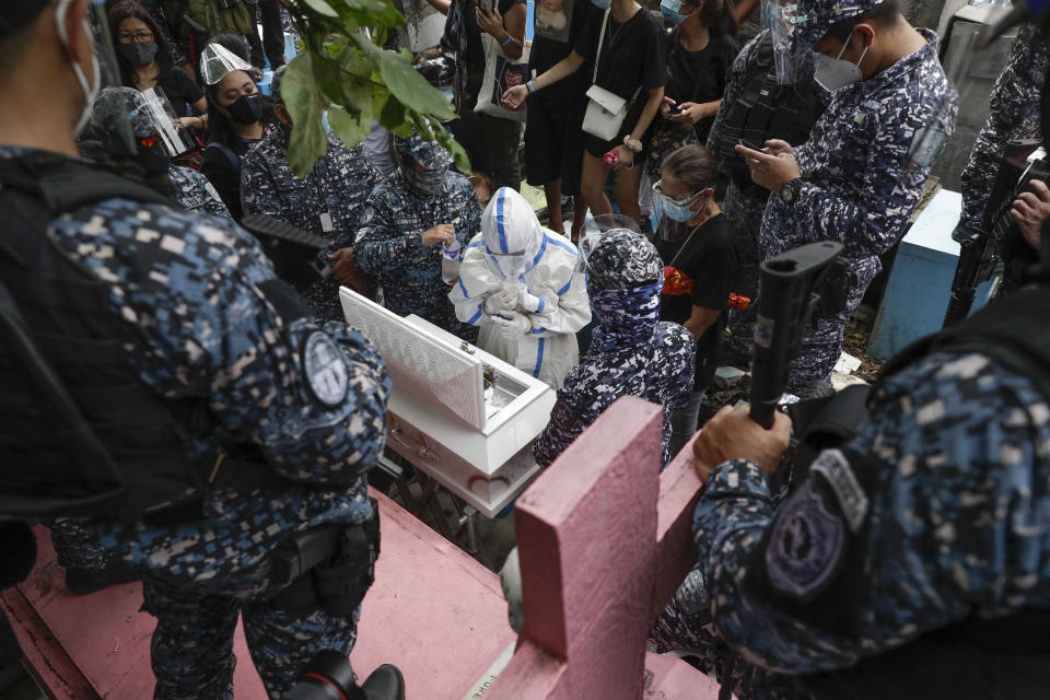 Police secure detained left-wing activist Reina Mae Nasino in handcuffs and wearing a protective suit to prevent the spread of the coronavirus walks as she attends funeral rites of her three-month-old firstborn named River at Manila's North Cemetery, Philippines on Friday Oct. 16, 2020. Left-wing groups on Friday decried the treatment as brutal of Nasino, who was allowed by a Manila court to attend her baby's burial but was restrained with handcuffs, a sweltering protective suit and swarms of armed escorts as she quietly wept. (AP Photo/Aaron Favila)