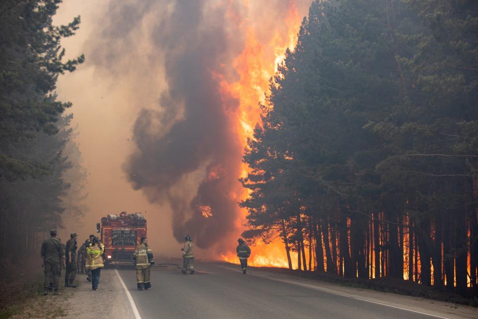 FILE - In this Wednesday, June 16, 2021 file photo, firefighters work at the scene of forest fire near Andreyevsky village outside Tyumen, western Siberia, Russia. Wildfires in Siberia are releasing record amounts of greenhouse gases, scientists say, contributing to global warming. Each year, thousands of wildfires engulf wide swathes of Russia, destroying forests and shrouding broad territories in acrid smoke. This summer has seen particularly massive fires in Yakutia in northeastern Siberia following unprecedented heat. (AP Photo/Maksim Slutsky, File)