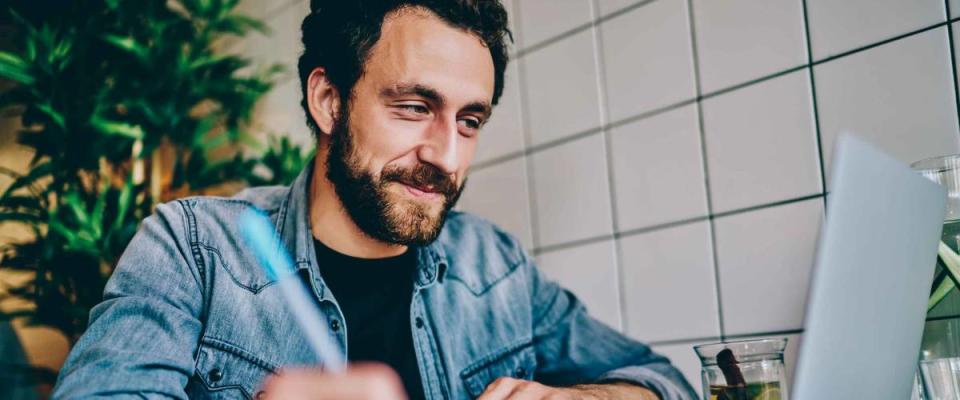 Cheerful bearded young man watching webinar online