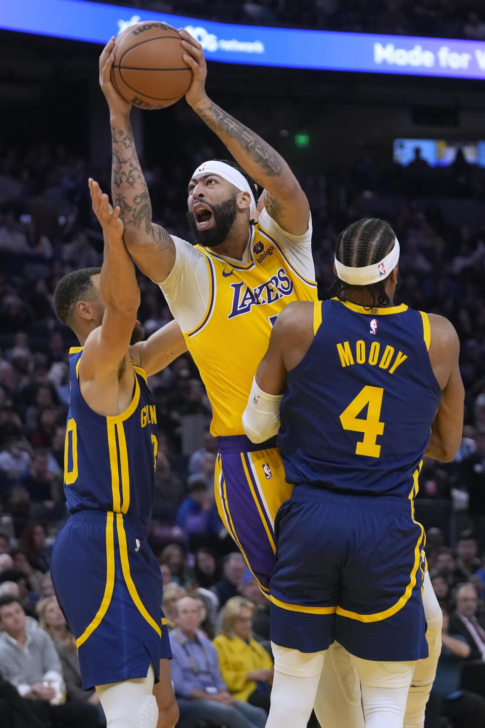 Los Angeles Lakers forward Anthony Davis, middle, shoots against Golden State Warriors guard Stephen Curry, left, and guard Moses Moody (4) during the first half of an NBA basketball game in San Francisco, Thursday, Feb. 22, 2024. (AP Photo/Jeff Chiu)