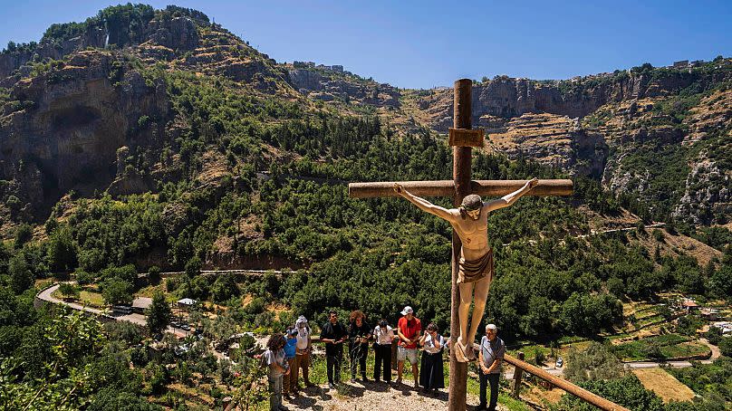 Lebanese priest Hani Tawk, centre, prays with French tourists and his family outside the Saint Elisha monastery in the Kadisha Valley, 22 July 2023.