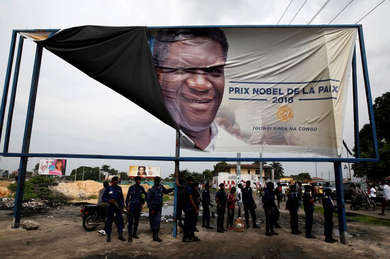 FILE PHOTO: Congolese police officers stand under a banner for 2018 Nobel Peace Prize Denis Mukwege after a political rally of Martin Fayulu, the runner-up in Democratic Republic of Congo's presidential election in Kinshasa
