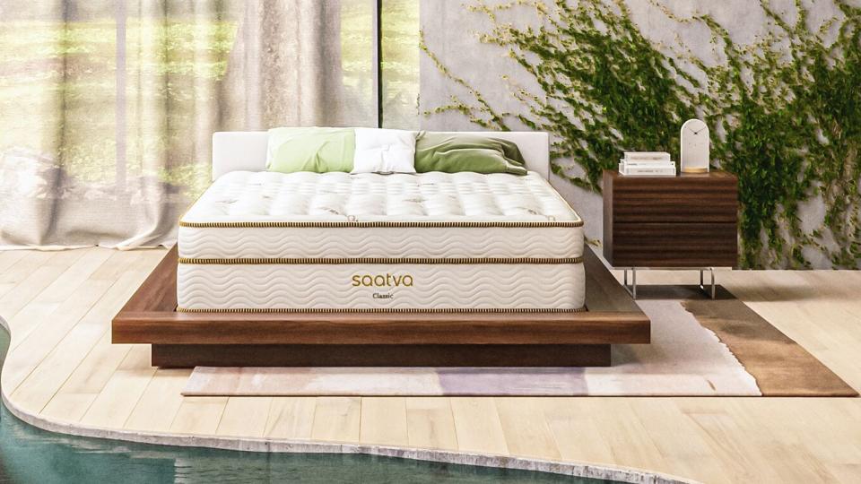 The Saatva Classic mattress photographed in a stylish white pool room with an indoor river