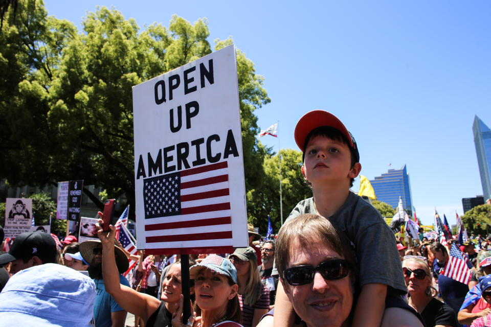 SACRAMENTO, CALIFORNIA, UNITED STATES - 2020/05/23: A protester holds a placard that says Wake Up America during the demonstration. Protesters gathered outside the California State Capitol to protest the California Stay-At-Home Orders and to call for the reopening of the California economy. (Photo by Stanton Sharpe/SOPA Images/LightRocket via Getty Images)