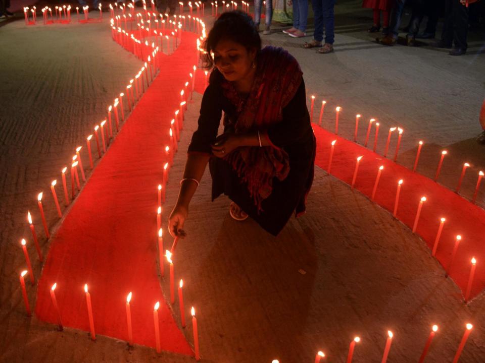 An Indian NGO volunteer lights candles placed on the ground in the shape of a red ribbon during an awareness rally on the eve of World Aids Day in Agartala, the capital of the northeastern state of Tripura, on 30 November 2017 (Arindam Dey/AFP/Getty)