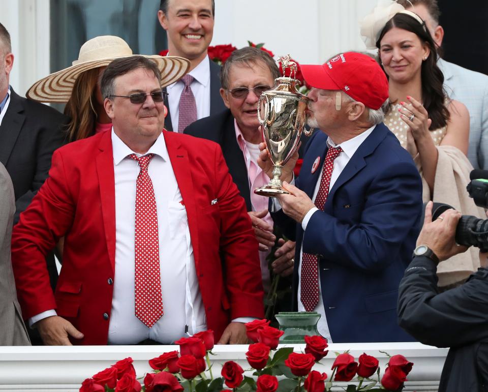 Rich Strike owner Rich Dawson, right, kissed the trophy in the winners circle as trainer Eric Reed looked on after they won the 148th Kentucky Derby at Churchill Downs in Louisville, Ky. on May 7, 2022.  