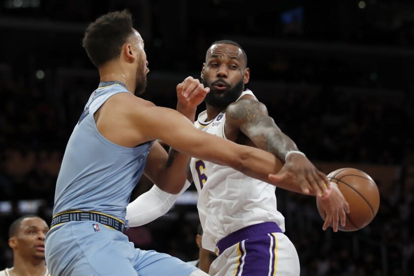 Memphis Grizzlies forward Kyle Anderson, front left, passes the ball past Los Angeles Lakers forward LeBron James, right, during the first half of an NBA basketball game Sunday, Jan. 9, 2022, in Los Angeles. (AP Photo/Alex Gallardo)