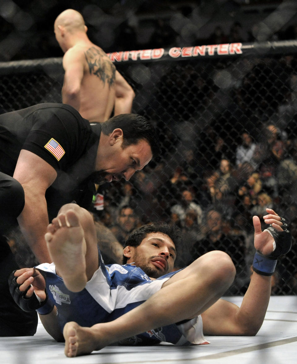 Adriano Martins lays on the canvas after being knocked out by Donald Cerrone background, during the lightweight bout of an UFC mixed martial arts match in Chicago, Saturday, Jan., 25, 2014. (AP Photo/Paul Beaty)