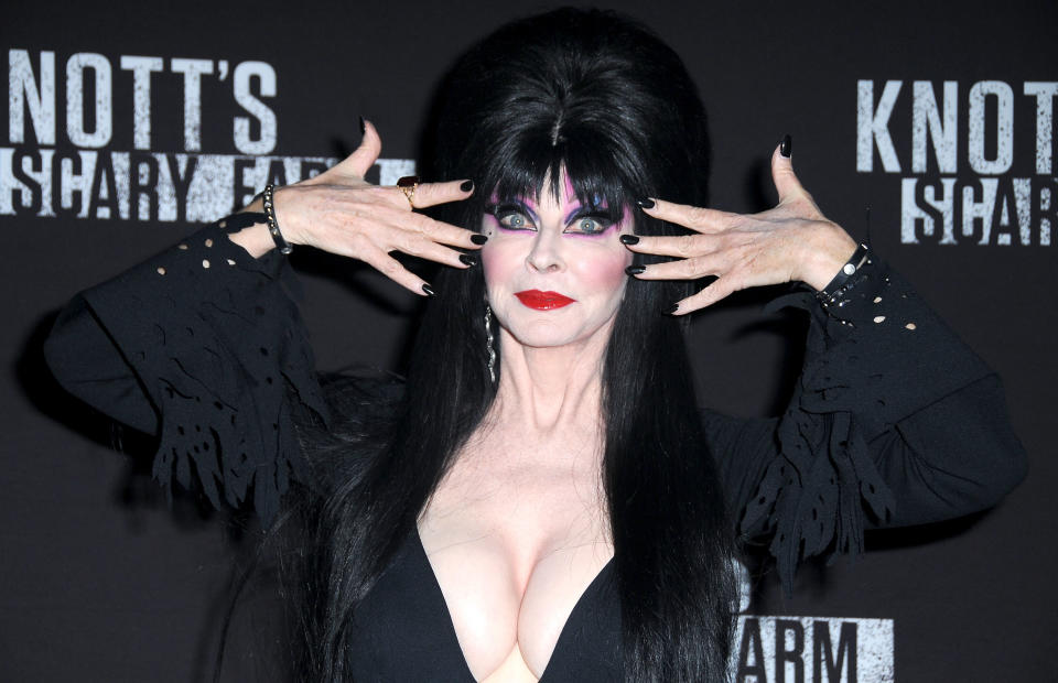 A closeup of Elvira holding her hands in front of her eyes
