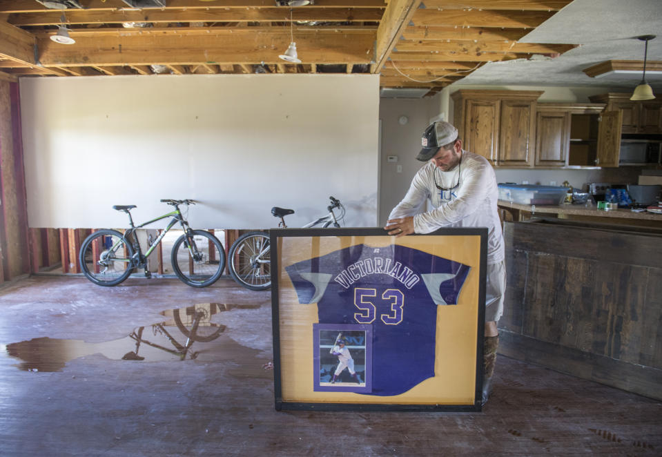 A former baseball player with LSU, Gerard Victoriano, Jr., salvages his old jersey the morning after Hurricane Delta passed over his house southeast of Lake Charles, La., on Saturday, Oct. 10, 2020. His house was originally destroyed by Hurricane Laura. Rain and floodwater from Hurricane Delta can still be seen on the floor of his gutted living room. (Chris Granger/The Advocate via AP)