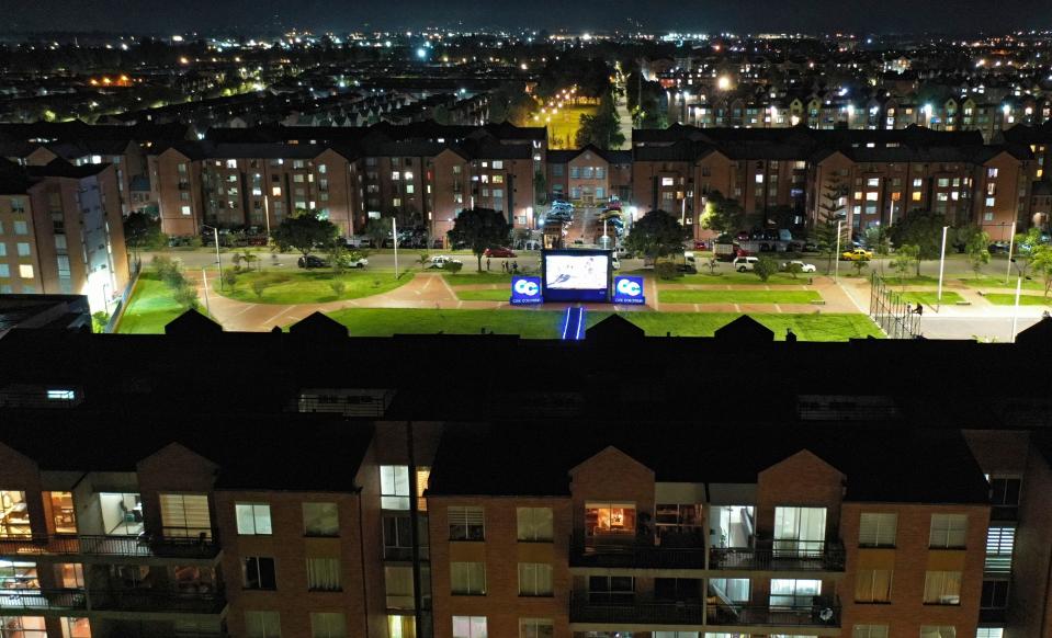 Aerial view as a film is projected on a giant screen at a park, so that quarantined people in their apartments watch a movie from home amid the coronavirus (COVID-19) pandemic, in Bogota, on April 23, 2020. - Colombia extended mandatory preventive isolation due to COVID-19 until at least May 11. (Photo by Raul ARBOLEDA / AFP) (Photo by RAUL ARBOLEDA/AFP via Getty Images)