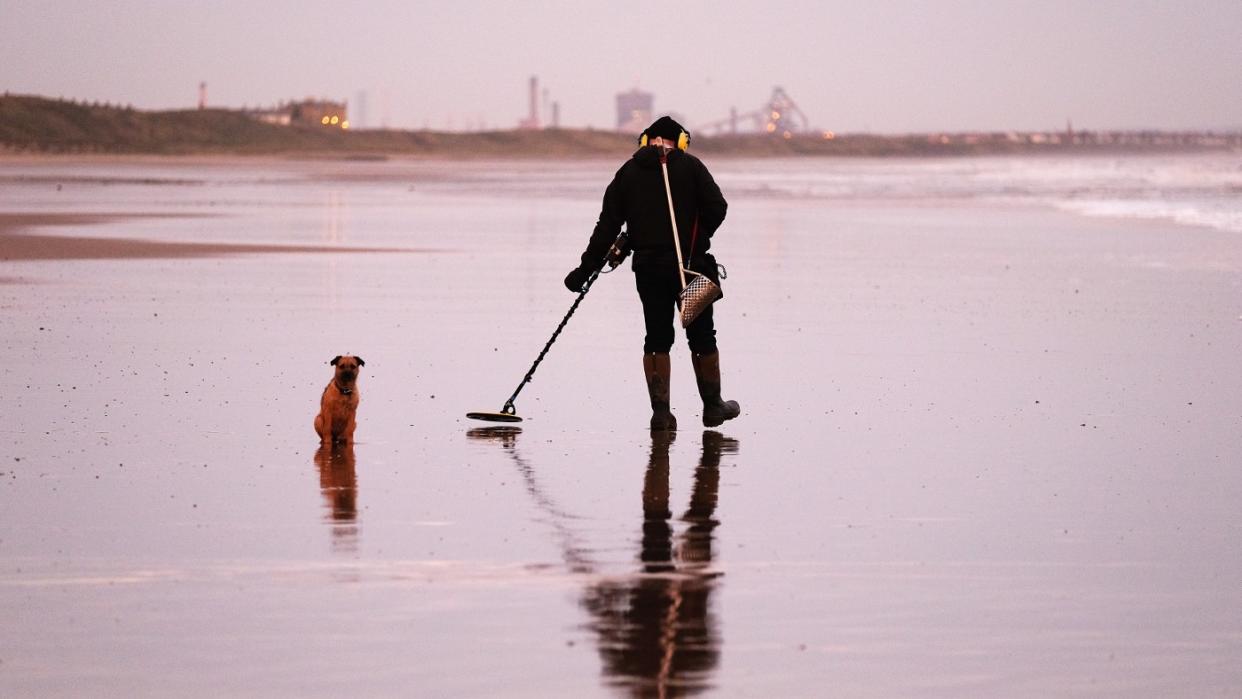  A man seeks treasure on a UK beach. 