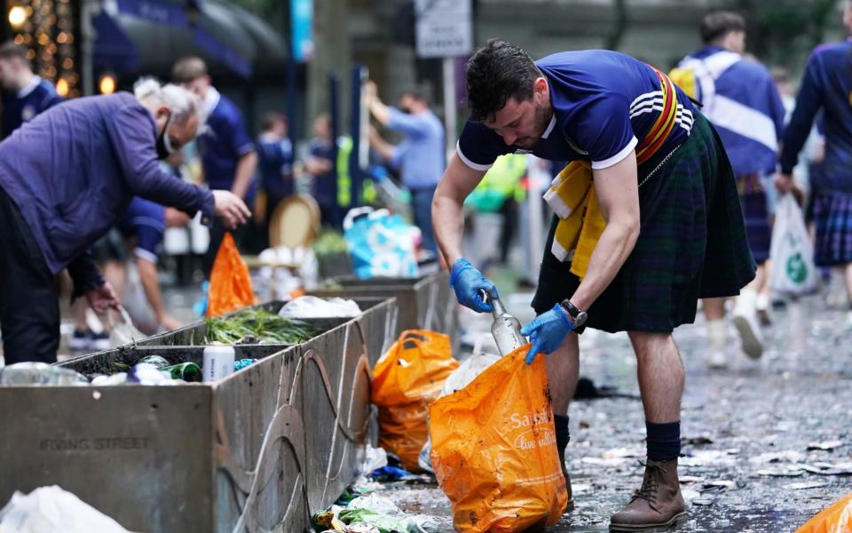 Scotland fans clean up litter in Leicester Square, London, ahead of the UEFA Euro 2020 Group D match between England and Scotland - PA