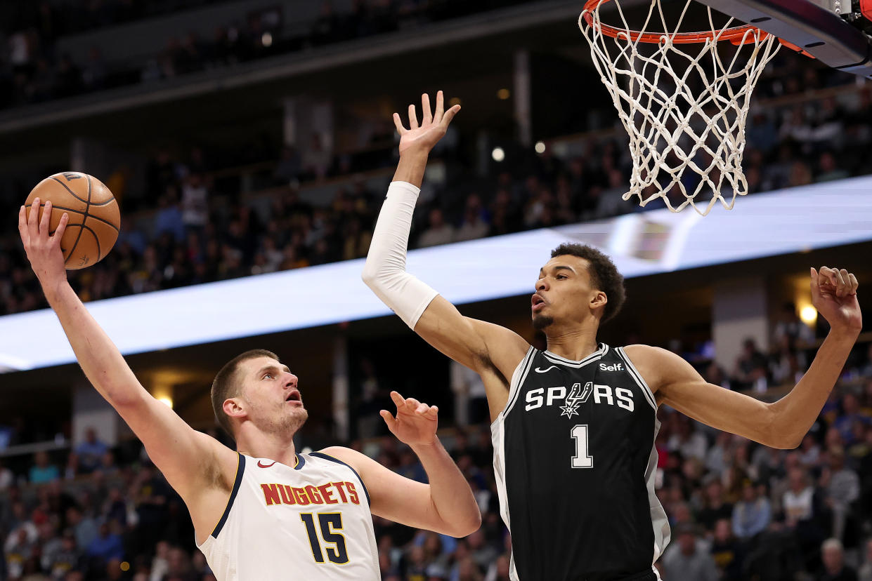 DENVER, COLORADO - APRIL 02: Nikola Jokic #15 of the Denver Nuggets goes to the basket against Victor Wembanyama #1 of the San Antonio Spurs during the first quarter at Ball Arena on April 02, 2024 in Denver, Colorado. NOTE TO USER: User expressly acknowledges and agrees that, by downloading and or using this photograph, User is consenting to the terms and conditions of the Getty Images License Agreement.   (Photo by Matthew Stockman/Getty Images)