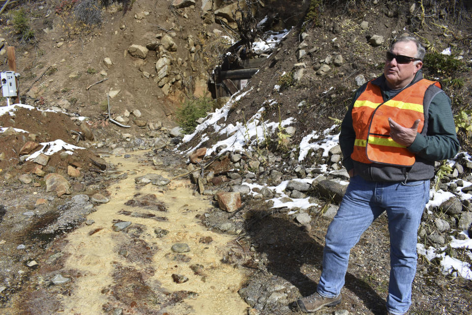 In this Oct. 12, 2018 photo, Tillman McAdams with the U.S. Environmental Protection Agency speaks about cleanup work at the Susie mine in Rimini, Mont., as polluted water from the mine flows near his feet. The mine is one of dozens that have fouled water supplies in the mountain community. (AP Photo/Matthew Brown)