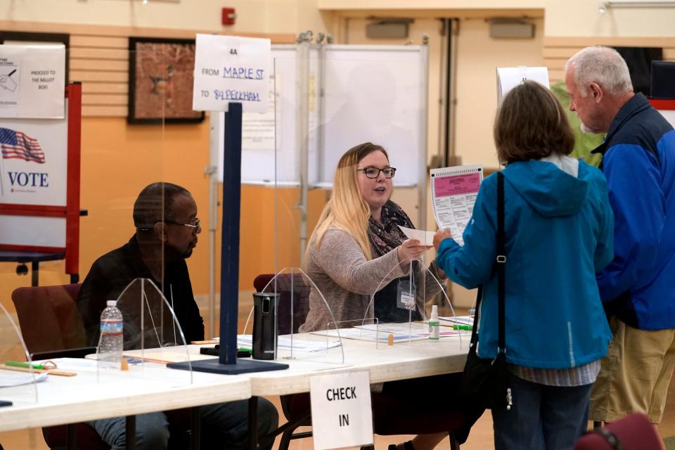 An election worker, center, assists voters, right, in the Massachusetts primary election at a polling place, Tuesday, Sept. 6, 2022, in Attleboro, Massachusetts.