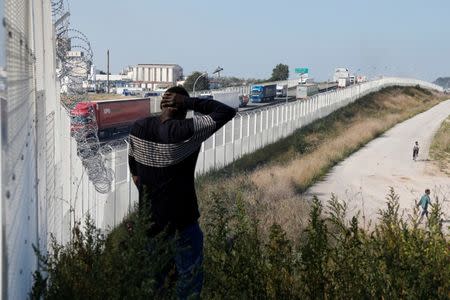 Migrant walks past the fence which secures the approach to the city from migrants trying to reach Britain, in Calais, France, September 21, 2016. REUTERS/Pascal Rossignol