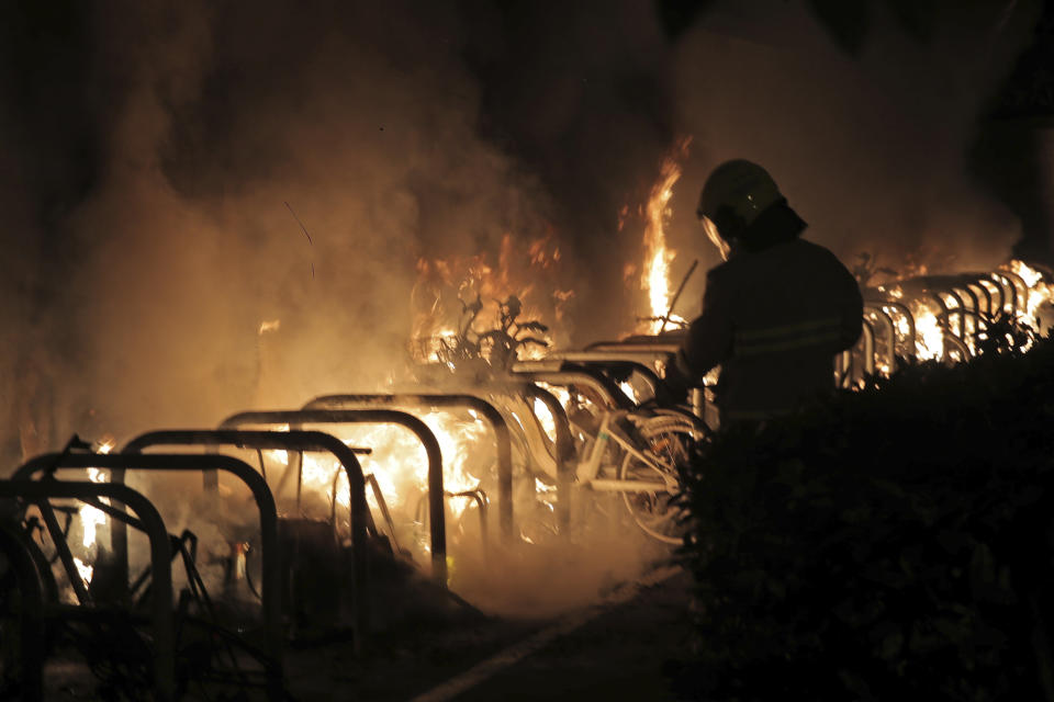 A fire fighter puts extinguishes a fire set by protesters in Hong Kong, early Saturday, Nov. 9, 2019. A Hong Kong university student who fell off a parking garage after police fired tear gas during clashes with anti-government protesters died Friday in a rare fatality in five months of unrest, fueling more outrage against authorities in the semi-autonomous Chinese territory. (AP Photo/Kin Cheung)