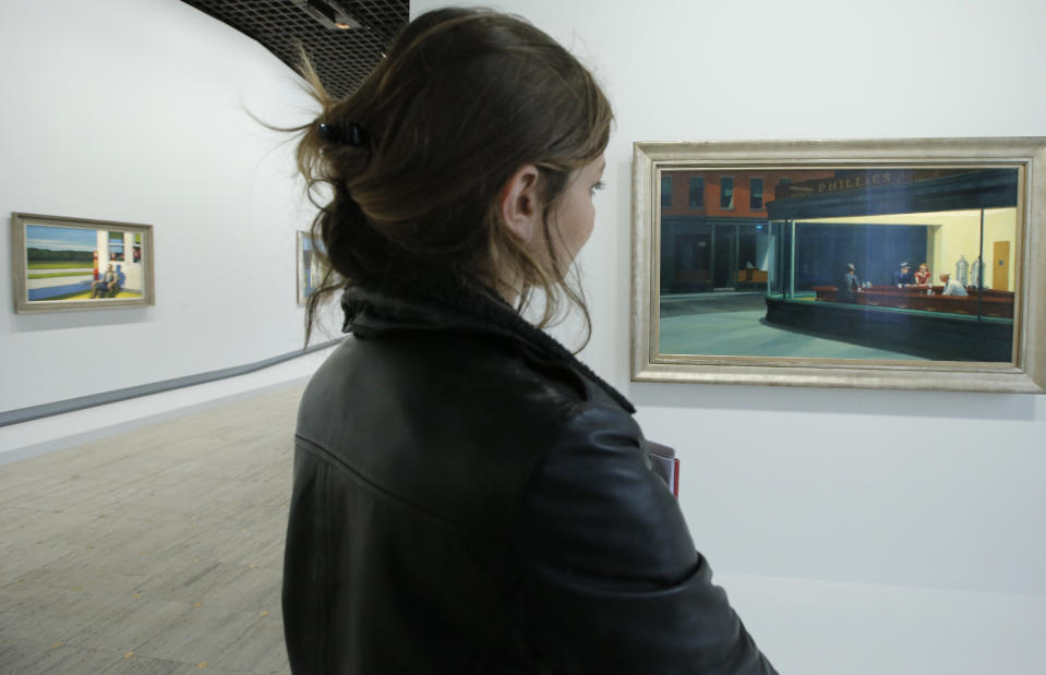 A woman looks at "Nighthawks, 1942", at right, as part of the retrospective of Edward Hopper, one of the great American 20th century artists at Paris’ Grand Palais Museum, in Paris, Monday, Oct. 8, 2012. This major Hopper retrospective reveals that the 20th century painter known for his rendering of American life, also drew inspiration from France, and includes some 128 Hopper works, such as the masterpieces “Nighthawks” and “Soir Bleu”.(AP Photo/Francois Mori)