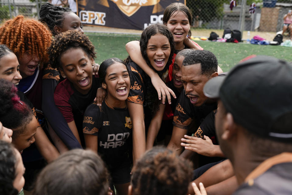 Young women and their coach Dioguinho bring it in for a team huddle at the start of a soccer training session run by the Bola de Ouro social program, at the Complexo da Alemao favela in Rio de Janeiro, Brazil, May 16, 2024. (AP Photo/Silvia Izquierdo)