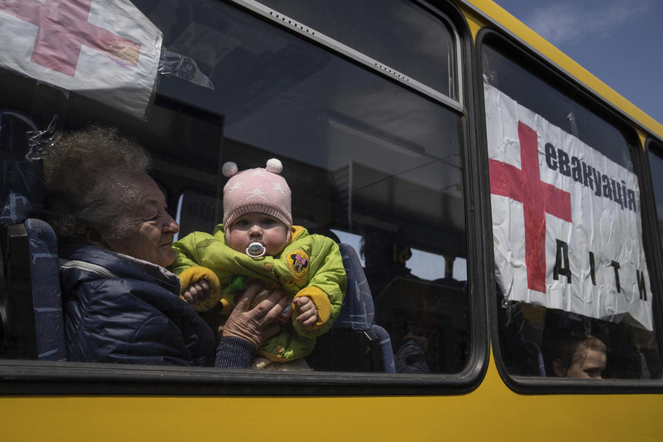 A woman with a child from Siversk look though the window of a bus during evacuation near Lyman, Ukraine, Wednesday, May 11, 2022. (AP Photo/Evgeniy Maloletka)