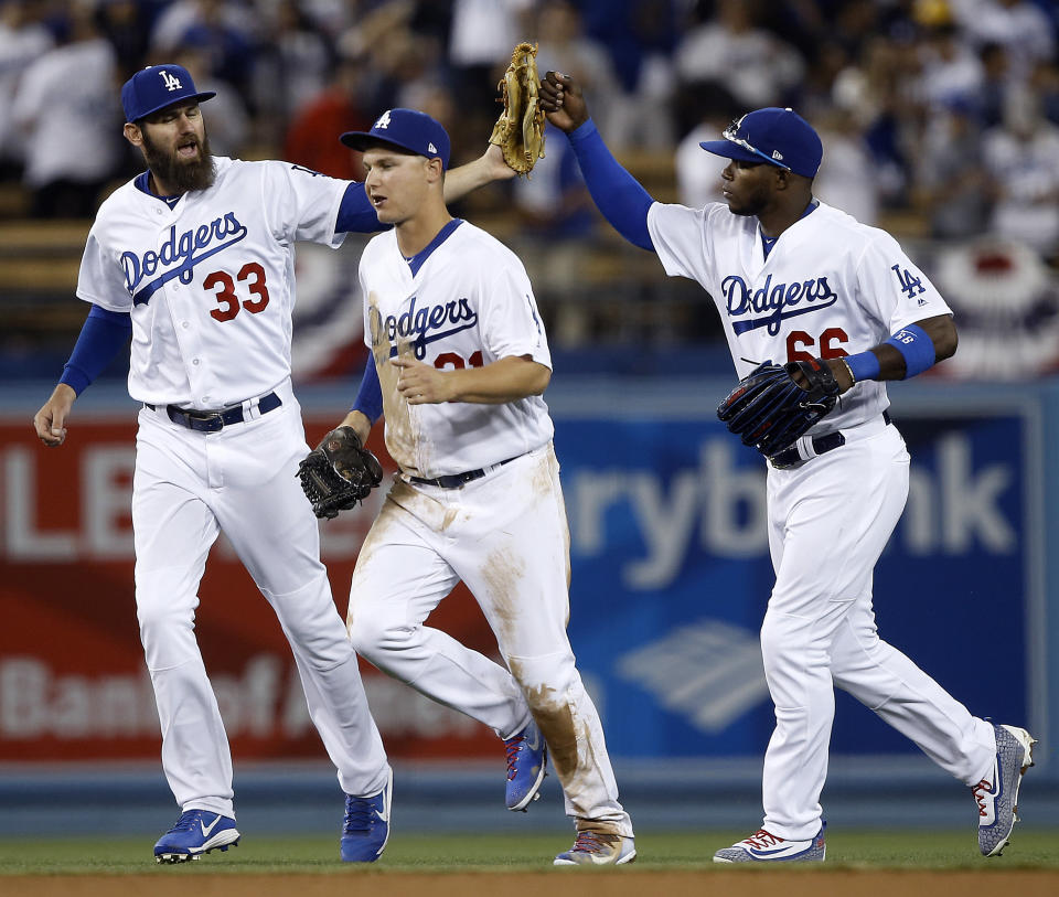 Los Angeles Dodgers left fielder Scott Van Slyke (33) and right fielder Yasiel Puig (66) celebrate with center fielder Joc Pederson after the Dodgers defeated the San Diego Padres 3-1 in a baseball game in Los Angeles, Wednesday, April 5, 2017. (AP Photo/Alex Gallardo)