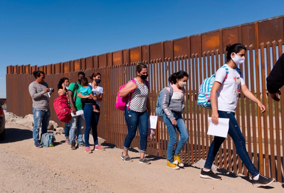A group of migrants walk around a gap in the U.S.-Mexico border in Yuma, Ariz., seeking asylum in the United States after crossing over from Mexico.