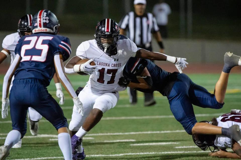 The Laguna Creek Cardinals’ Tariq Booth (17) runs the ball seven yard before being tackled by the Pleasant Grove Eagles’ Erik Clark (7) in the first half of the game on Friday, Sept. 8, 2023, at Sheldon High School.