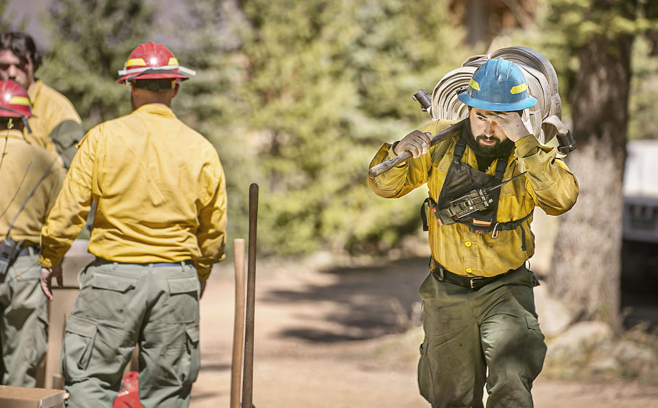 Firefighters with Structure Group 4 hook up hoses to a sprinkler system to protect homes in the Loma Linda neighborhood off highway 518 north of the Taos County line as firefighters from all over the country converge on Northern New Mexico to battle the Hermit's Peak and Calf Canyon fires on May 13, 2022. (Jim Weber/Santa Fe New Mexican via AP)