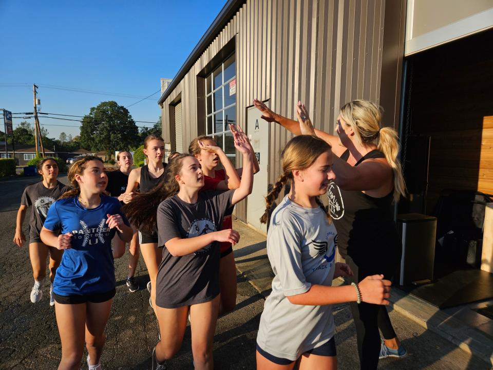 FemFit Redding coach Mikilah Speer (right) high fives members of the U-Prep girls volleyball team after a group sprint around her gym on Tuesday, July 25, 2023.