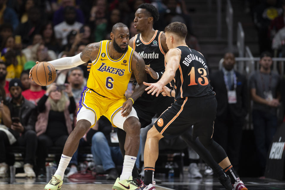 Los Angeles Lakers forward LeBron James (6) is double-teamed by Atlanta Hawks guard Bogdan Bogdanovic (13) and forward Onyeka Okongwu, center, during the second half of an NBA basketball game, Friday, Dec. 30, 2022, in Atlanta. (AP Photo/Hakim Wright Sr.)