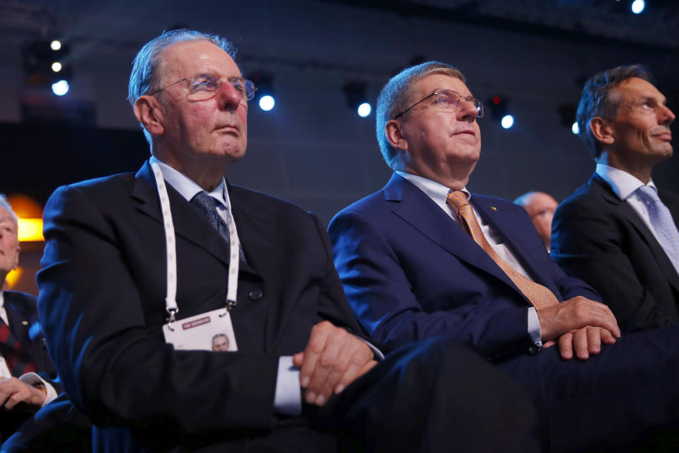 FILE - In this Friday, July 31, 2015 file photo, Honorary President of the International Olympic Committee (IOC) Jacques Rogge, left, sits along with IOC President Thomas Bach, at the 128th IOC session in Kuala Lumpur, Malaysia. The International Olympic Committee on Sunday, Aug. 29, 2021 says Jacques Rogge who led the organization as president for 12 years, has died. He was 79. (AP Photo/Vincent Thian, file)