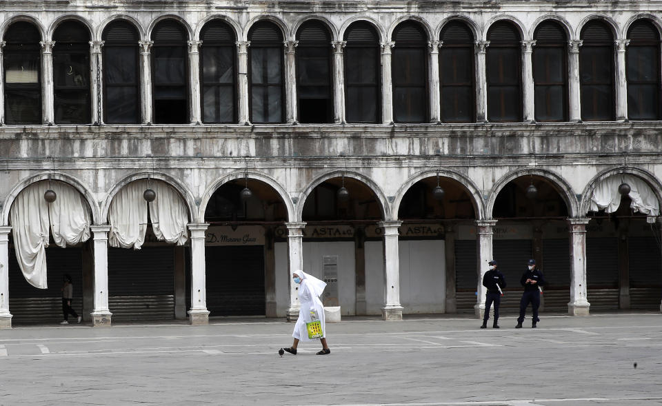 In this picture taken on Wednesday, May 13, 2020, a nun wearing a sanitary mask walks along St. Mark's Square in Venice, Italy. Venetians are rethinking their city in the quiet brought by the coronavirus pandemic. For years, the unbridled success of Venice's tourism industry threatened to ruin the things that made it an attractive destination to begin with. Now the pandemic has ground to a halt Italy’s most-visited city, stopped the flow of 3 billion euros in annual tourism-related revenue and devastated the city's economy. (AP Photo/Antonio Calanni)