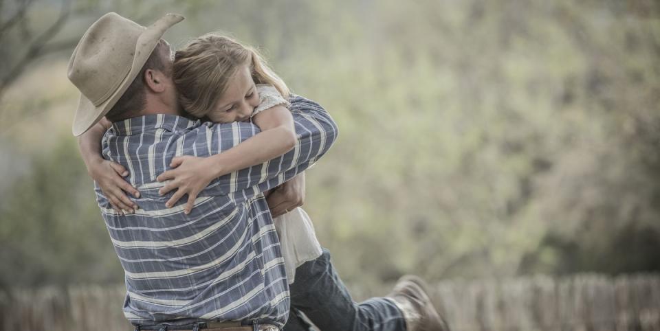 father wearing cowboy hat lifting and hugging daughter