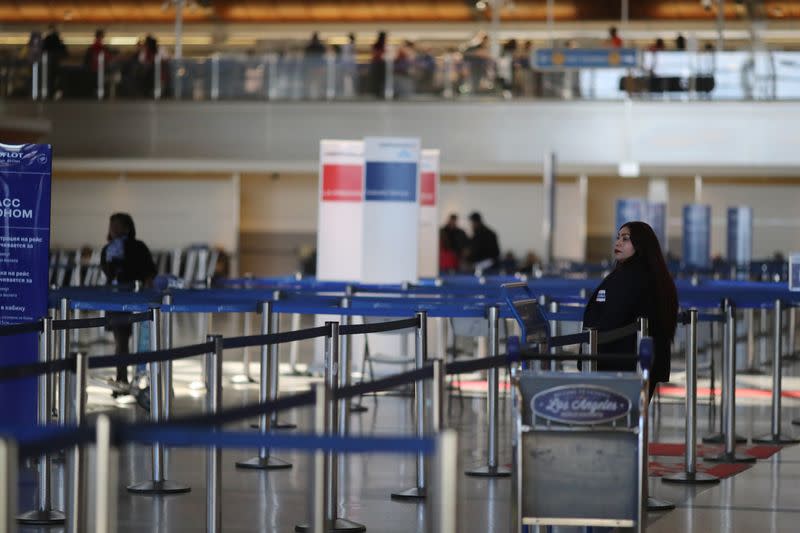 An airline worker stands in the empty international terminal at LAX airport in Los Angeles